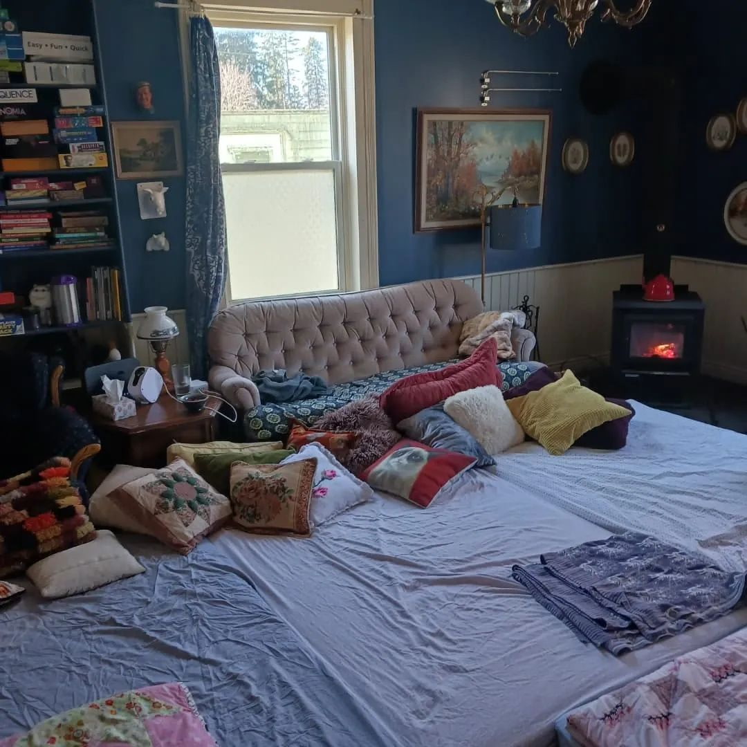 A cozy living room arranged with floor cushions and blankets