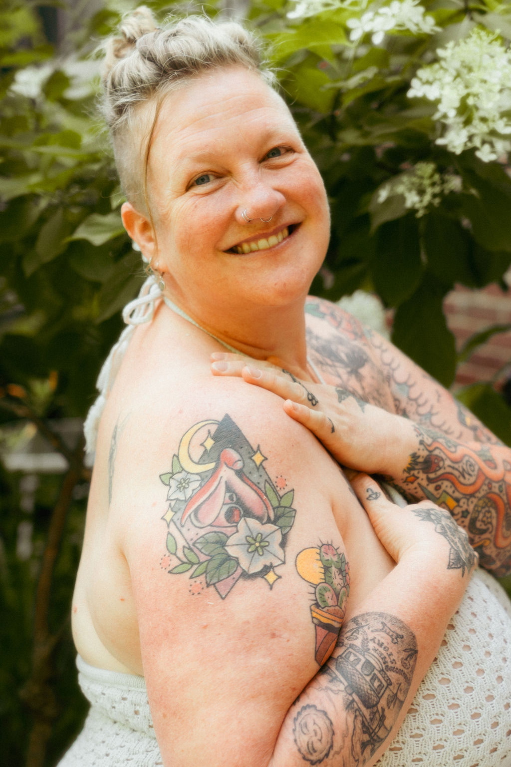 Sara smiling outdoors among flowering greenery